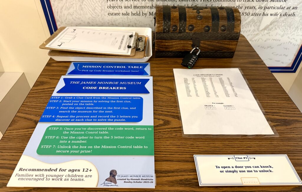 A table displays a clipboard, a wooden chest with a lock, code-breaking instruction sheets, and a cipher table at the James Monroe Museum&mdash;one of the fun things to do in Fredericksburg with kids.