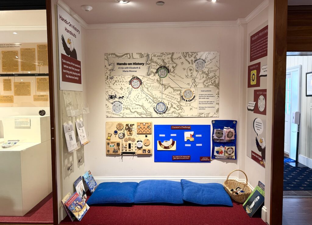 Children&rsquo;s history activity corner with wall displays, interactive boards, blue floor cushions, and a basket of books&mdash;one of the top things to do in Fredericksburg with kids for hands-on learning and fun.