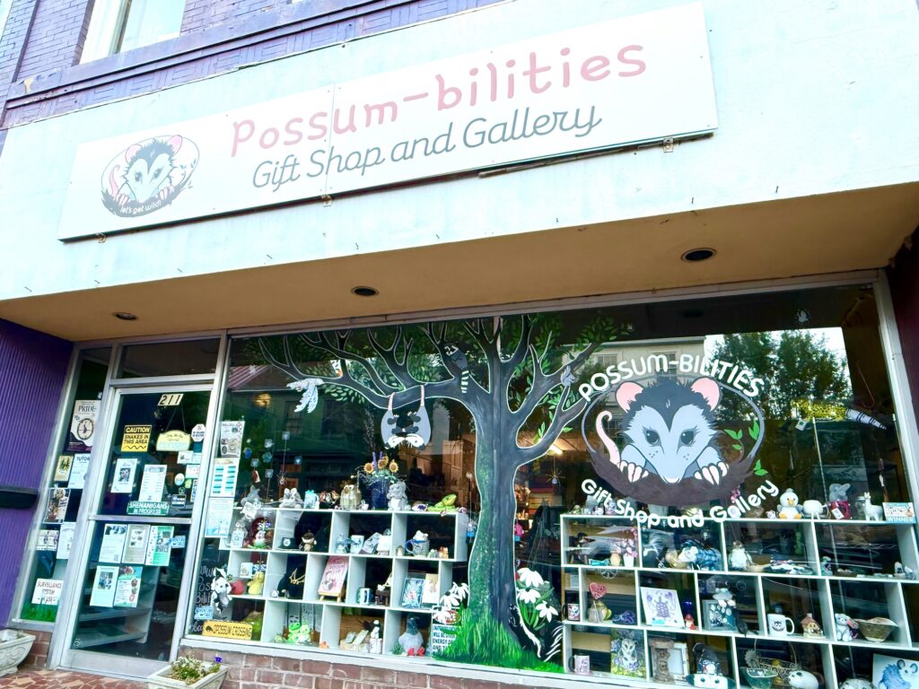 Storefront of "Possum-bilities Gift Shop and Gallery" with a large possum mural, tree artwork, and display shelves filled with various items&mdash;one of the fun things to do in Fredericksburg with kids.