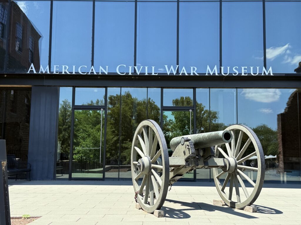 An old cannon is displayed outside the glass entrance of the American Civil War Museum, with the museum name visible above the doors.