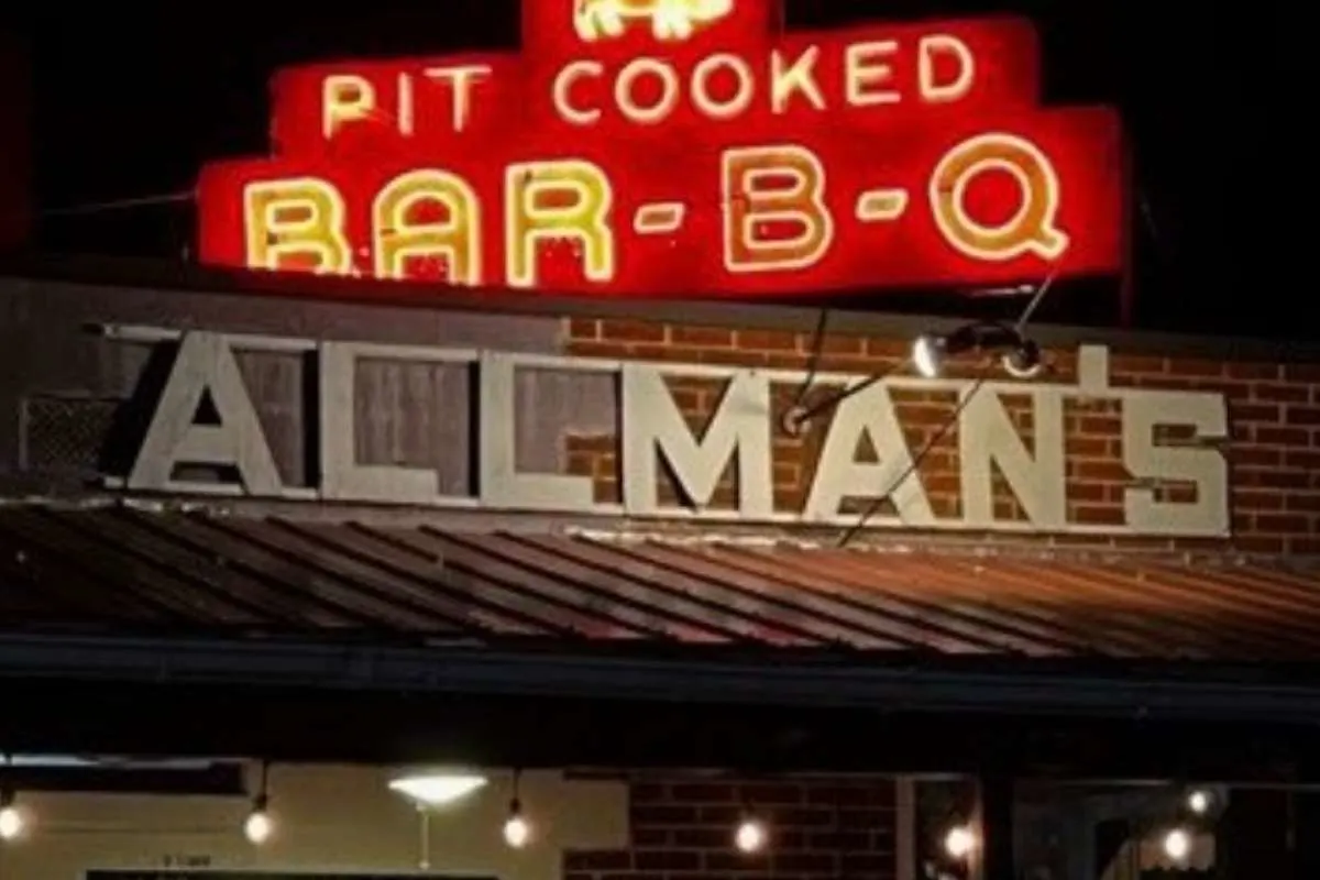 neon sign at night reading Alllman's pit-cooked BAR B Q