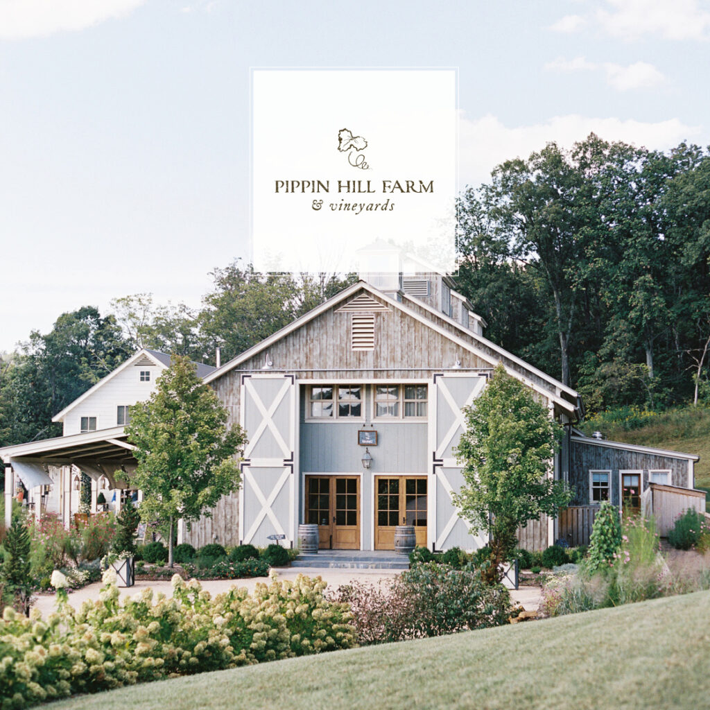 A rustic barn-style building at Pippin Hill Farm & Vineyards, one of the most charming wineries near Charlottesville, surrounded by greenery and landscaped gardens on a sunny day.