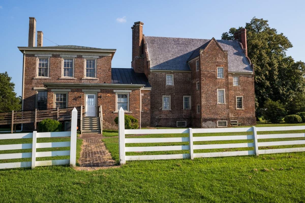 brickk manor house surrounded by white fence