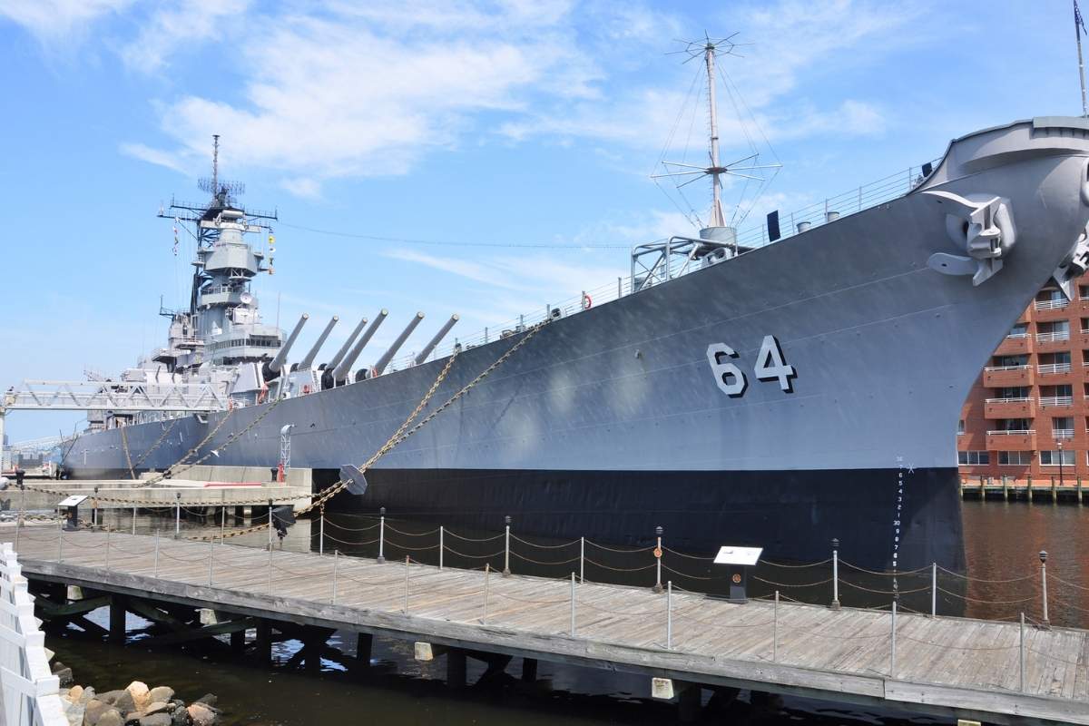 large metal battleship docked at shore