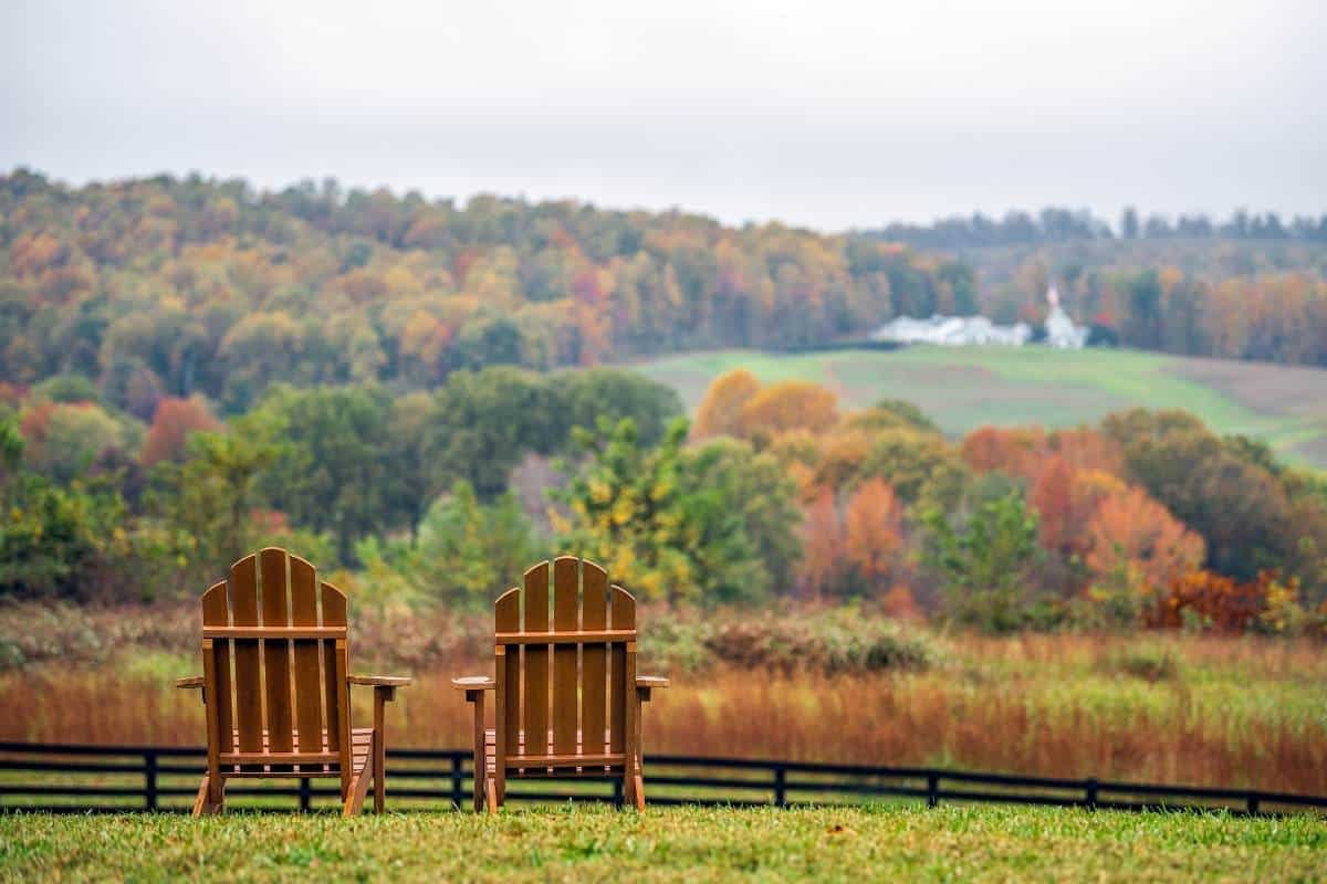 2 wooden adirondack chairs overlooking mountains
