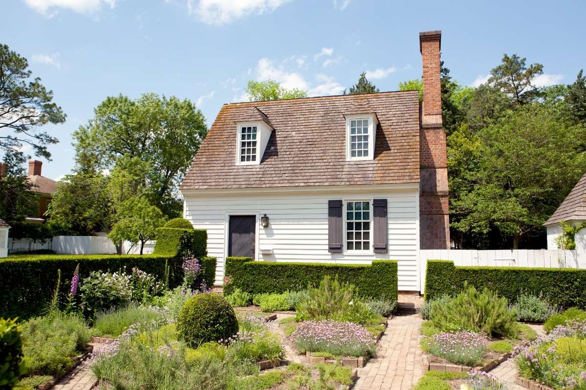 quaint colonial cottage with brick walkways and herb garden in front