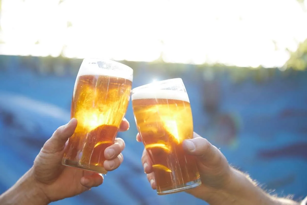 two hands holding glass of craft beer