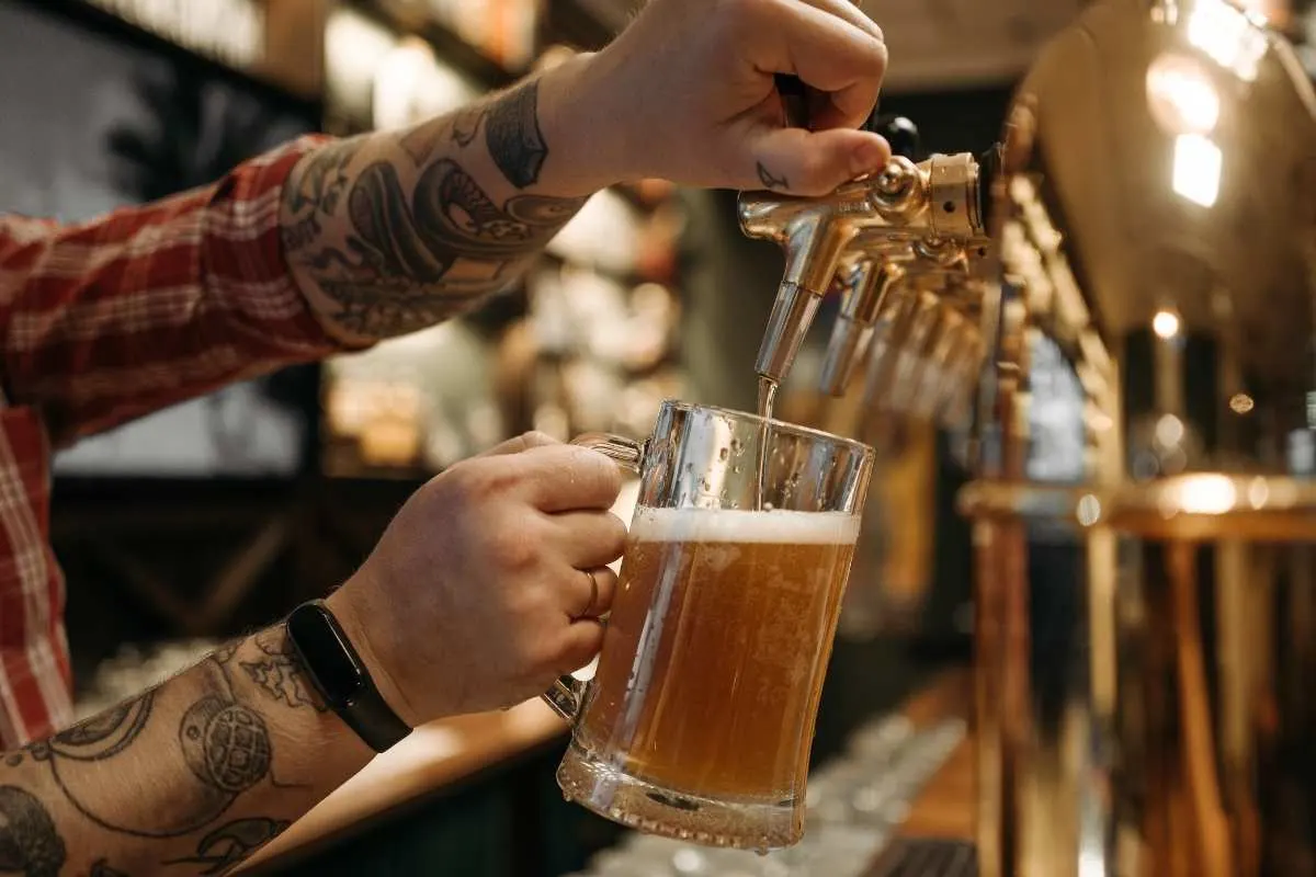 man pouring beer into glass mug