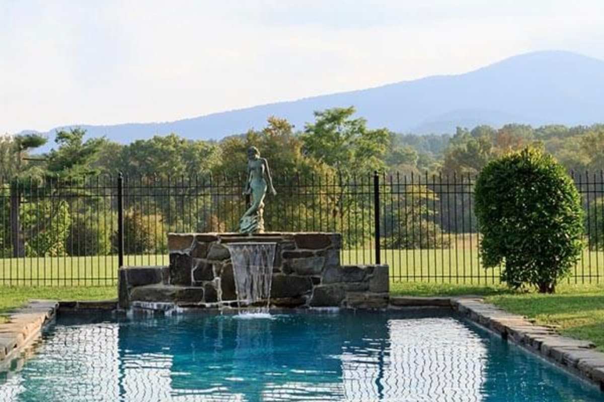 pool with fountain and statue in front of blue ridge mountains