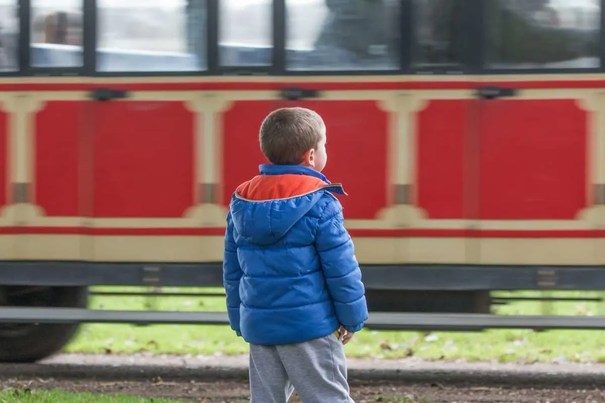 boy in front of red caboose car