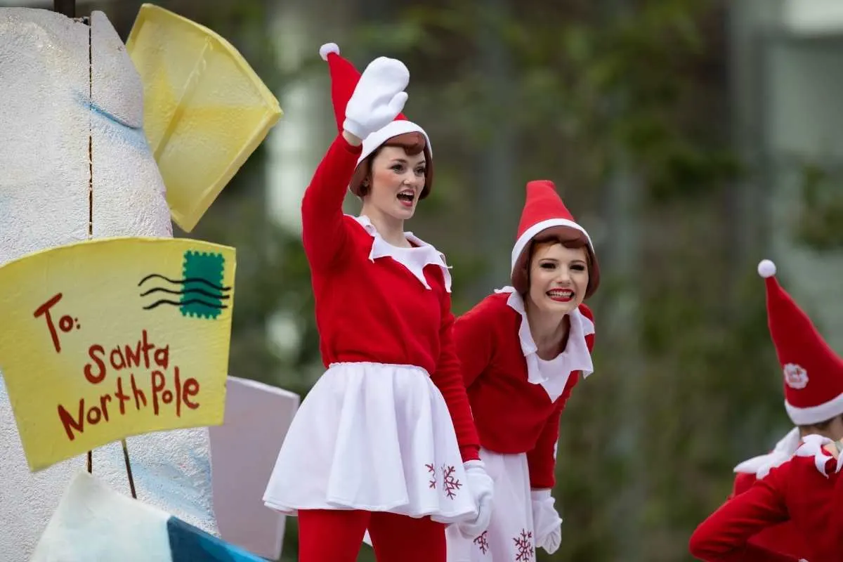 elves and mrs claus waving to crowd on parade float