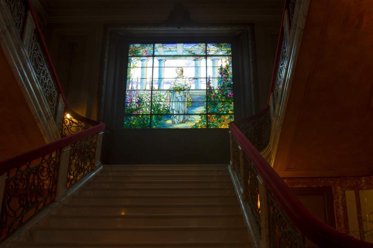 stained glass window of woman at top of stair landing