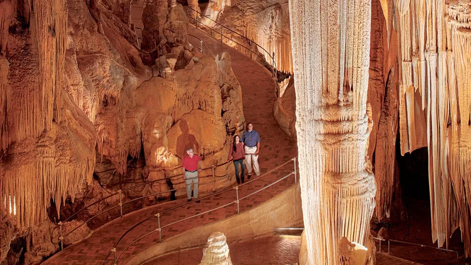 Two people standing in a cavern with stalactites and stalagmites.