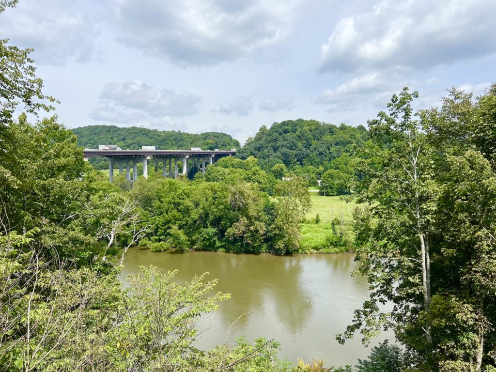 A scenic view of a river and trees, with a bridge in the background at Shot Tower State Park.
