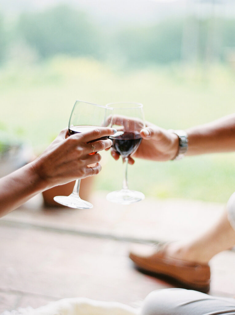 Two people toasting wine glasses outdoors.
