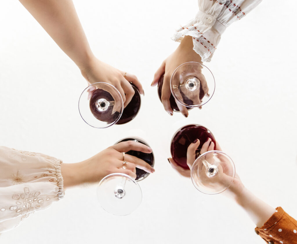 A group of women holding wine glasses in a circle.