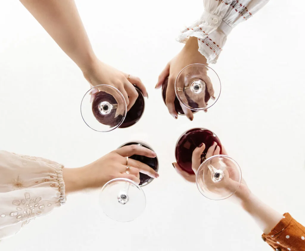 A group of women holding wine glasses in a circle.