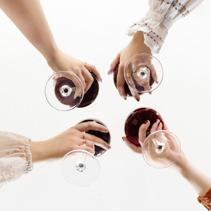 A group of women holding wine glasses in a circle.