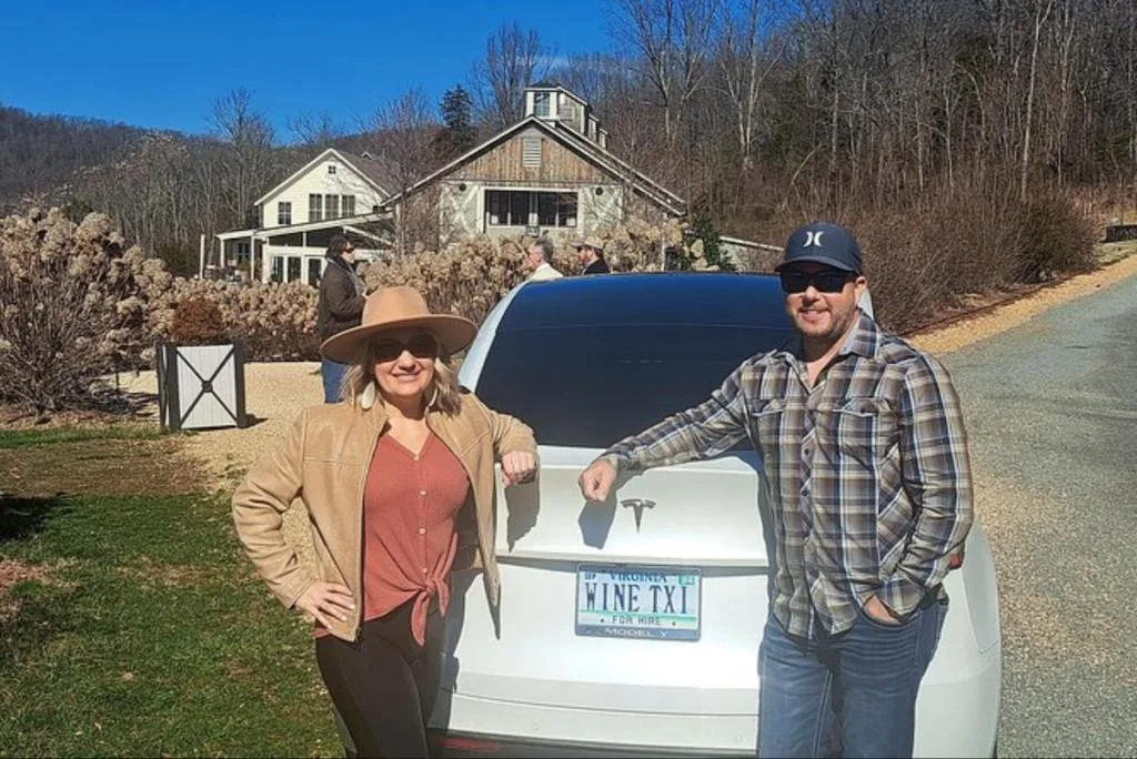 Two people standing next to a tesla model s.